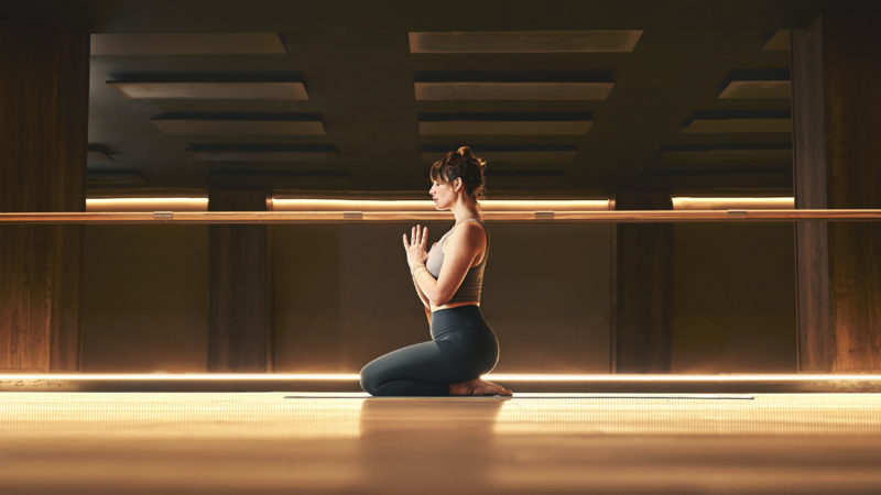 Woman kneeling on a yoga mat in a Third Space Mind and Body studio